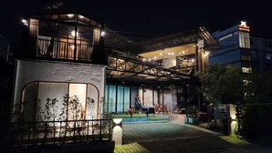 A modern building with a glass facade, outdoor seating area, and a well-lit entrance. - Capital O 75422 Million Pillows  (Chiang Mai)