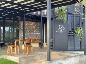 A modern outdoor seating area with wooden stools and a cushioned bench, a map mural on the wall, and a sign for 'Million Pillows Chiang Mai'. - Capital O 75422 Million Pillows  (Chiang Mai)