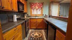 Una cocina con armarios de madera, una isla central y un tapete estampado con motivos de estrellas.