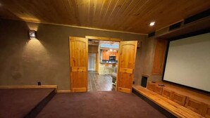 Una habitación acogedora con techo de madera, una pantalla grande y suelo alfombrado.