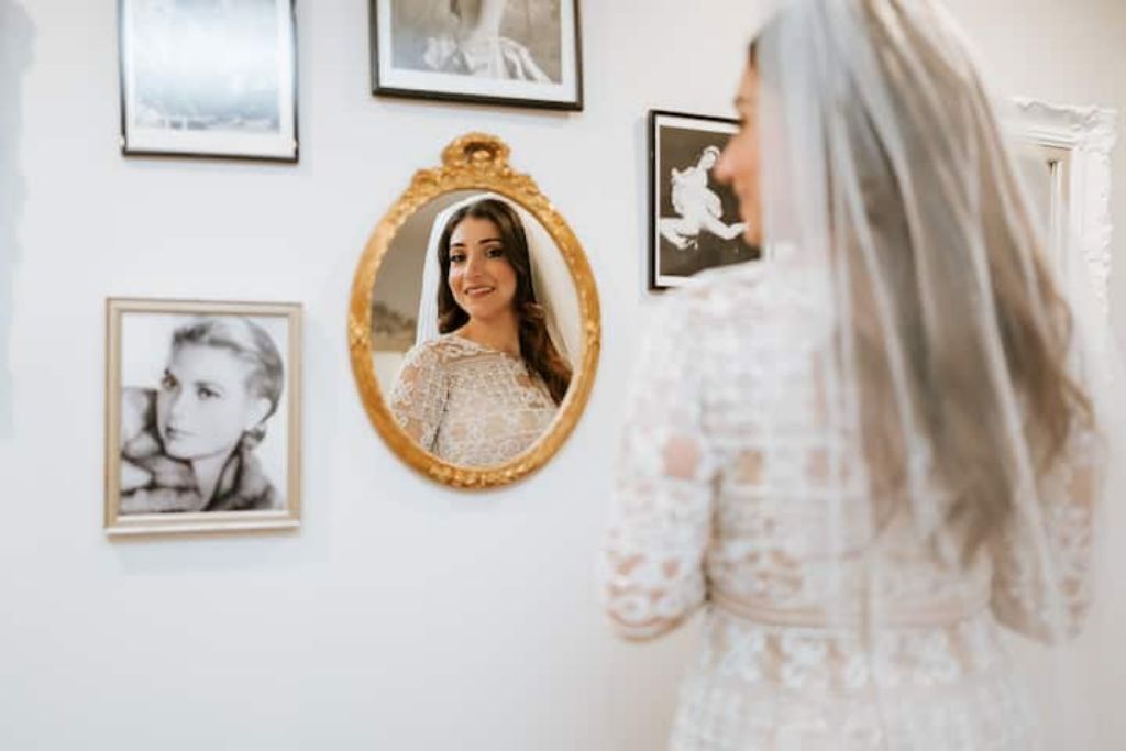 A room with a white wall, framed pictures, and a mirror.