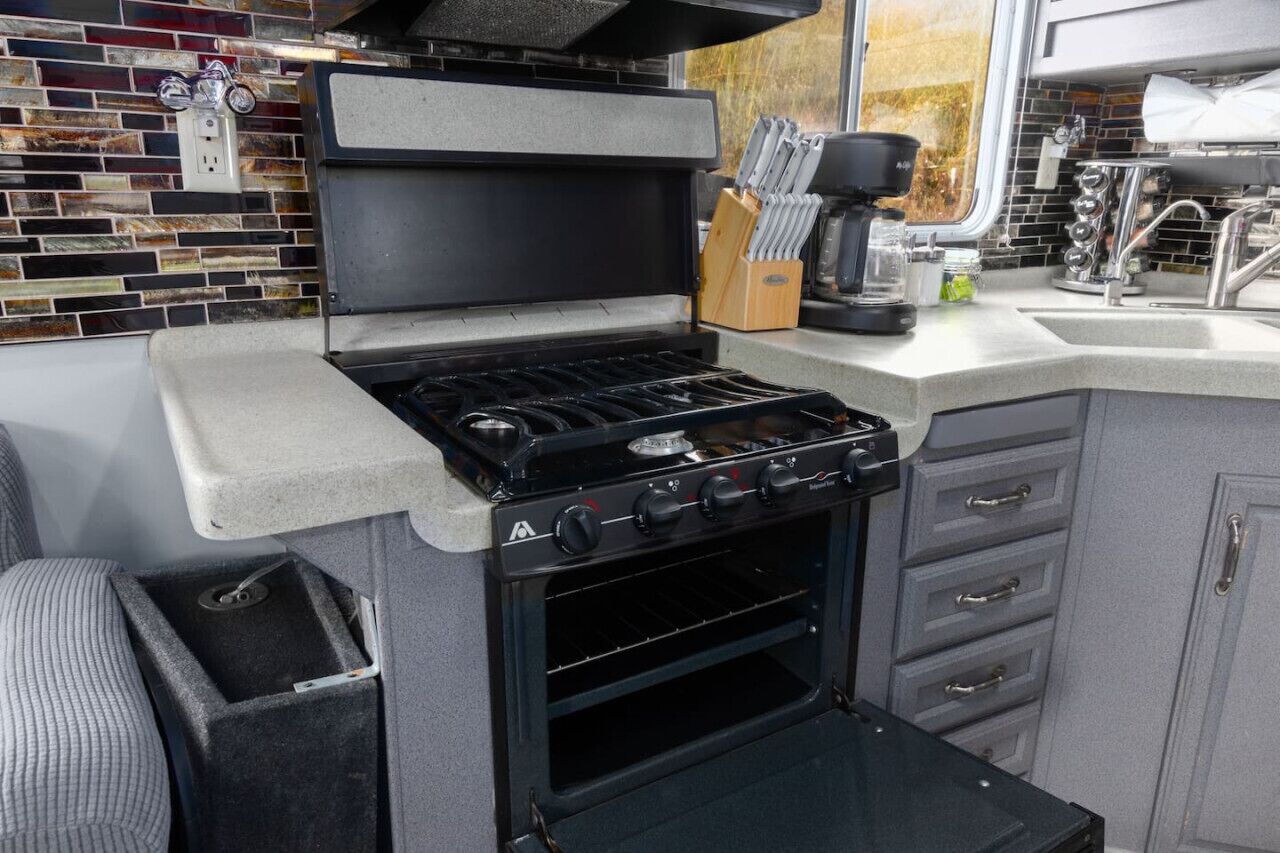 Una cocina compacta con estufa a gas integrada, horno y una pequeña encimera.