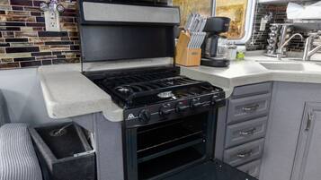 Una cocina compacta con estufa a gas integrada, horno y una pequeña encimera.