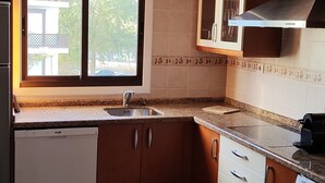 Cocina compacta con lavavajillas, lavadora, pileta y ventana que proporciona luz natural.