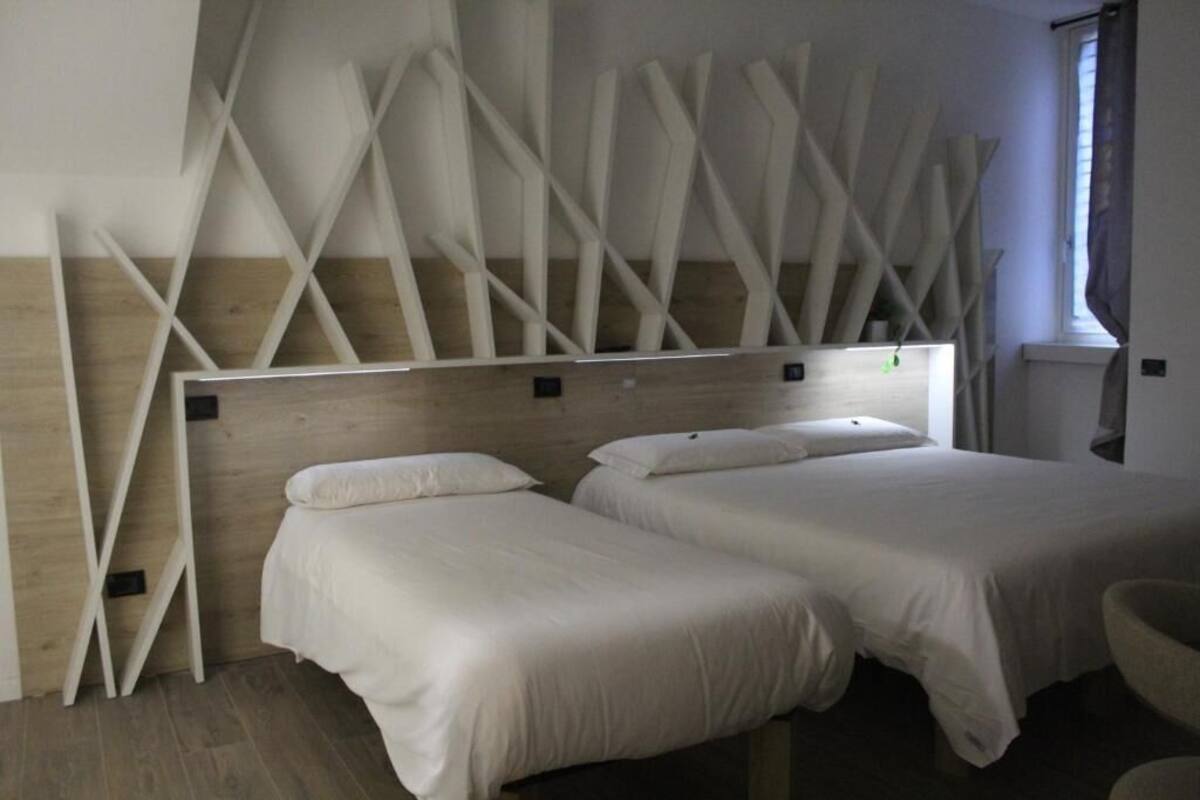 A hotel room with two beds, wooden headboard, and a modern design.