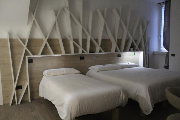 A hotel room with two beds, wooden headboard, and a modern design.