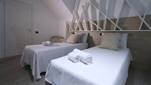 Two single beds with white linens and pillows, a wooden headboard, and a geometric wall design. - affittacamere i due cavalieri (Turin)