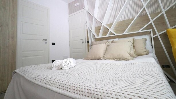 A bedroom with a bed, two doors, and a wooden panel wall. - affittacamere i due cavalieri (Turin)