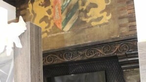 A fireplace with a TV screen, a decorative wall with lion motifs, and a wooden structure in the foreground. - affittacamere i due cavalieri (Turin)