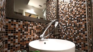 A bathroom with a white sink, a mirror, and mosaic tile walls. - affittacamere i due cavalieri (Turin)