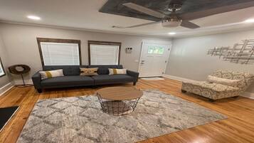 A living room with a grey sofa, patterned armchair, and a round coffee table.