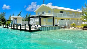 A beachfront property with a large yellow building, a dock, and clear turquoise water. - Your favorite getaway place (Bimini)