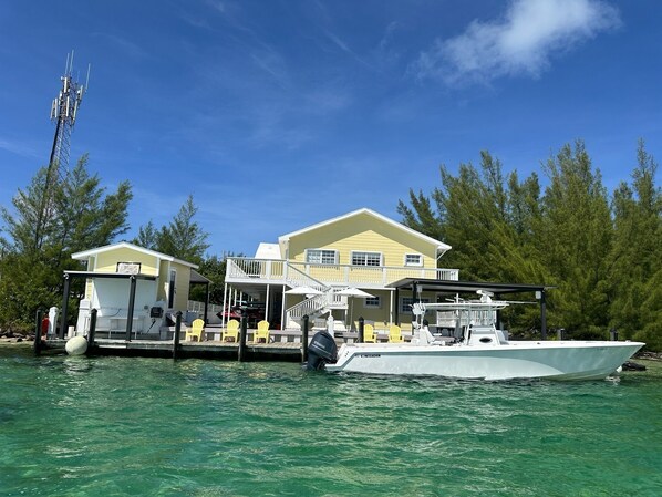 A waterfront property with a large house, docked boat, and outdoor seating area. - Your favorite getaway place (Bimini)
