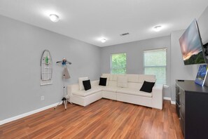 Relax in this stylish living room with a large L-shaped sofa, flat-screen TV, and side table.