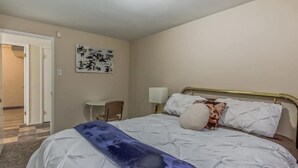 Une chambre à coucher comprenant un lit, une chaise, un bureau et une lampe fixée au mur.