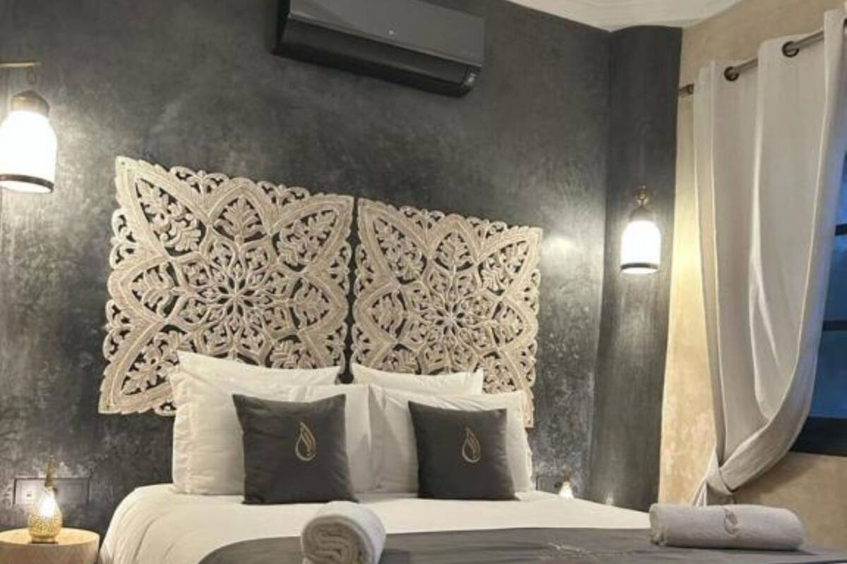A neatly made bed with a decorative headboard, bedside lamps, and a small table.