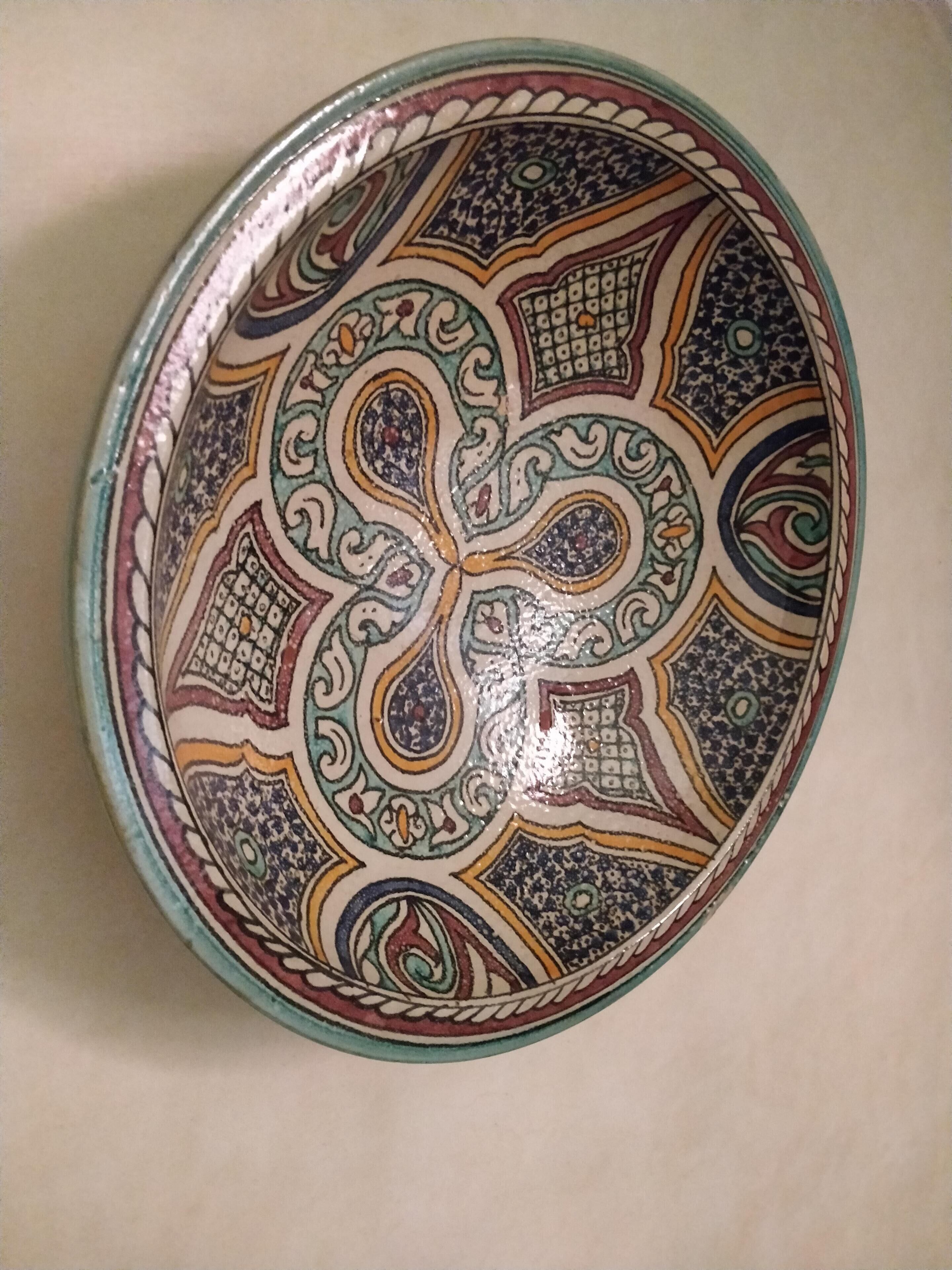 Un plato decorativo con diseños elaborados y un borde metálico.