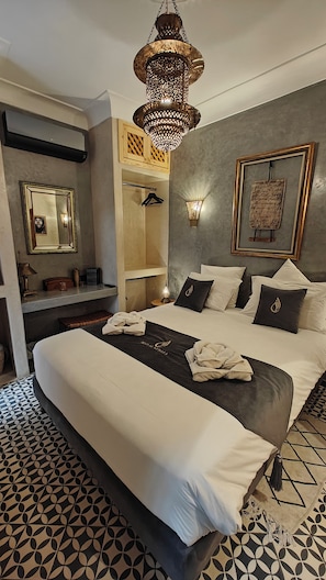 Una habitación de hotel moderna con una cama grande, una lámpara colgante, un armario y un espejo adosado a la pared.