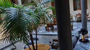 Un vaste espace intérieur doté d’un coin salon central, de grandes colonnes et d’un balcon agrémenté de balustrades décoratives.