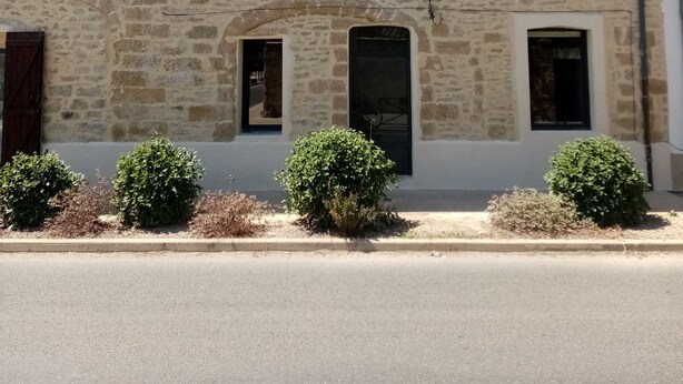 Un bâtiment en pierre avec un toit recouvert de tuiles, de nombreuses fenêtres et une porte.