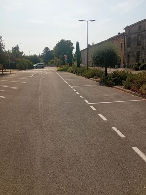 Een rustige straat met geparkeerde auto, lantaarnpaal en gebouwen aan één kant.