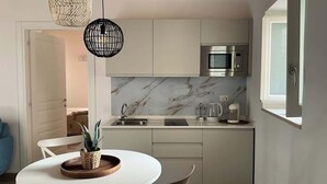 A compact kitchen with a white countertop, a built-in microwave, and a marble backsplash. - RUA 39 fine apartments 3 (Syracuse)