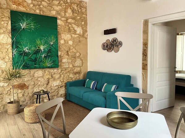 Una sala de estar acogedora con un sofá color turquesa, una mesa blanca y una pared de piedra.