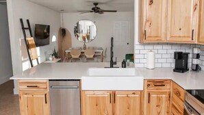 A modern kitchen with wooden cabinets, a white countertop, and a built-in dishwasher. - 2 minutes to downtown! Hill Country Luxury Duplex TX Wine Trail - Home B (Johnson City)