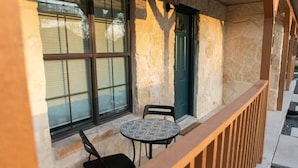 A stone building with a green door, a window with blinds, and a small table with two chairs. - 2 minutes to downtown! Hill Country Luxury Duplex TX Wine Trail - Home B (Johnson City)