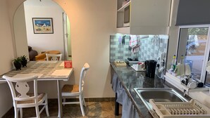 A modern kitchen with a dining area, featuring a tiled backsplash, granite countertops, and a dining table with chairs. - Mispa George - Self Catering Apartment - Sleeps 2 (George)
