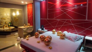 Una habitación de hotel moderna con una cama grande, un tocador con espejo y una pared de acento roja.