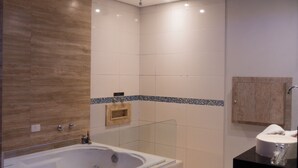 Un baño moderno con una bañera grande, cabina de ducha de vidrio y tocador negro.
