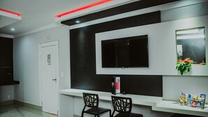 Una cocina moderna con televisión integrada, dos sillas negras y una encimera blanca.