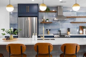 A modern kitchen with stainless steel appliances, a central island with bar seating, and pendant lighting.