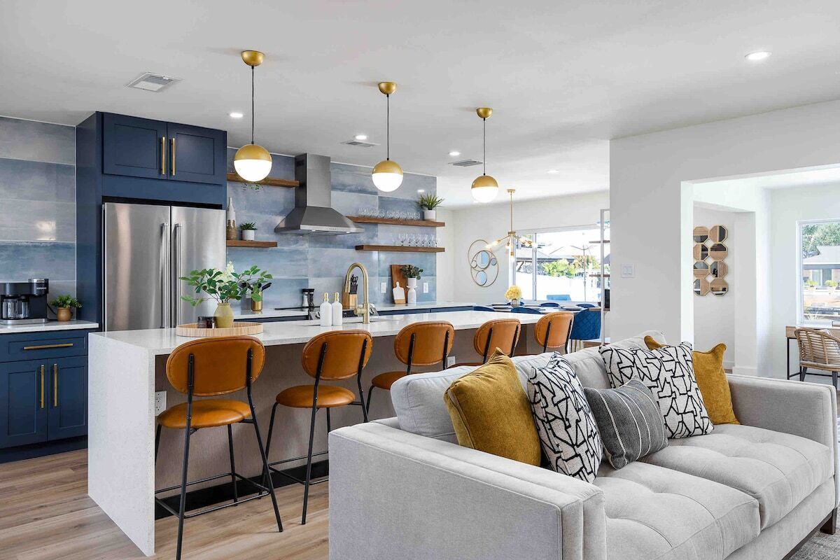 Une cuisine moderne dotée d’un îlot central, de tabourets de bar et de luminaires suspendus.