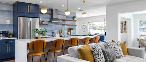 Een moderne keuken met een centraal eiland, barkrukken en hanglampen.