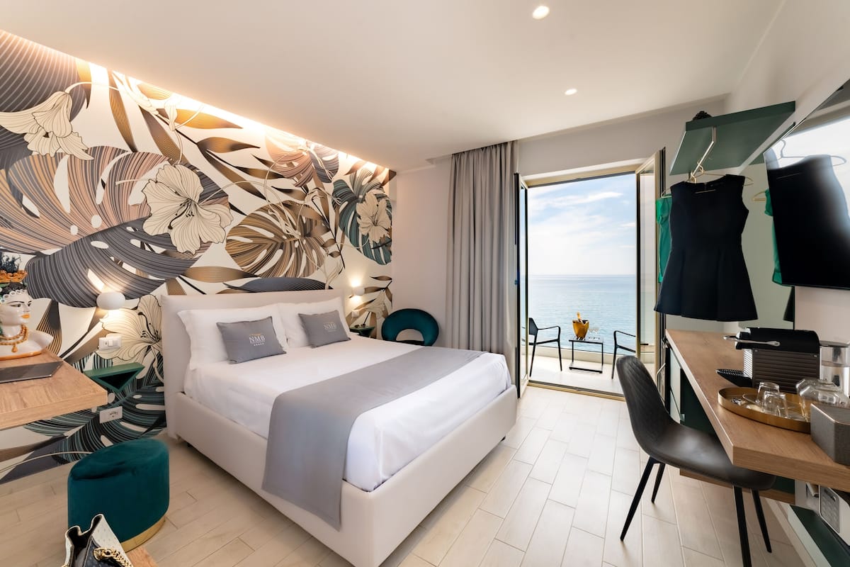 Une chambre d’hôtel moderne avec un grand lit, un bureau et une vue sur la mer.