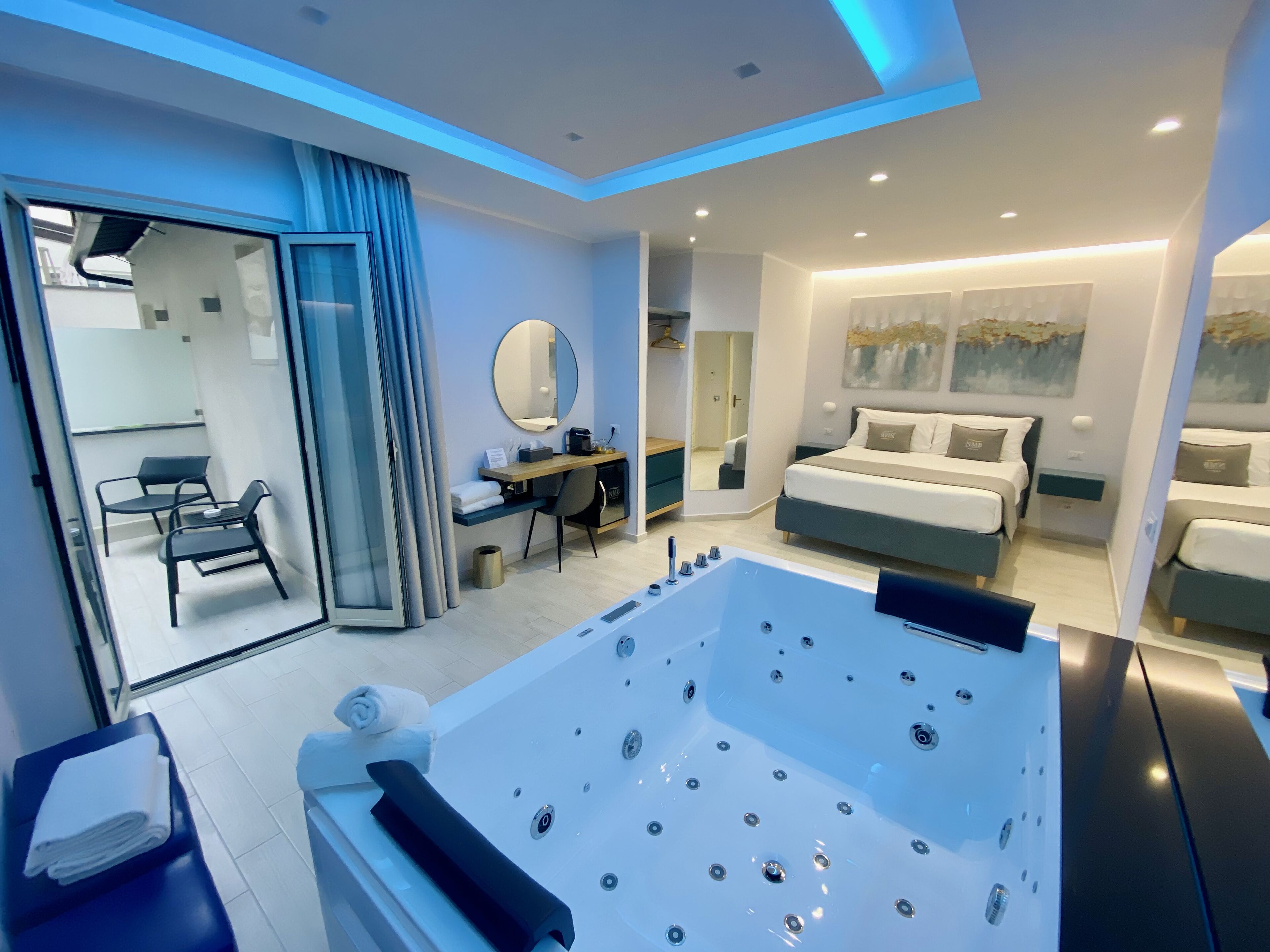 Une chambre d’hôtel moderne dotée d’une grande baignoire, d’un bureau avec une chaise, d’un lit et d’un miroir.