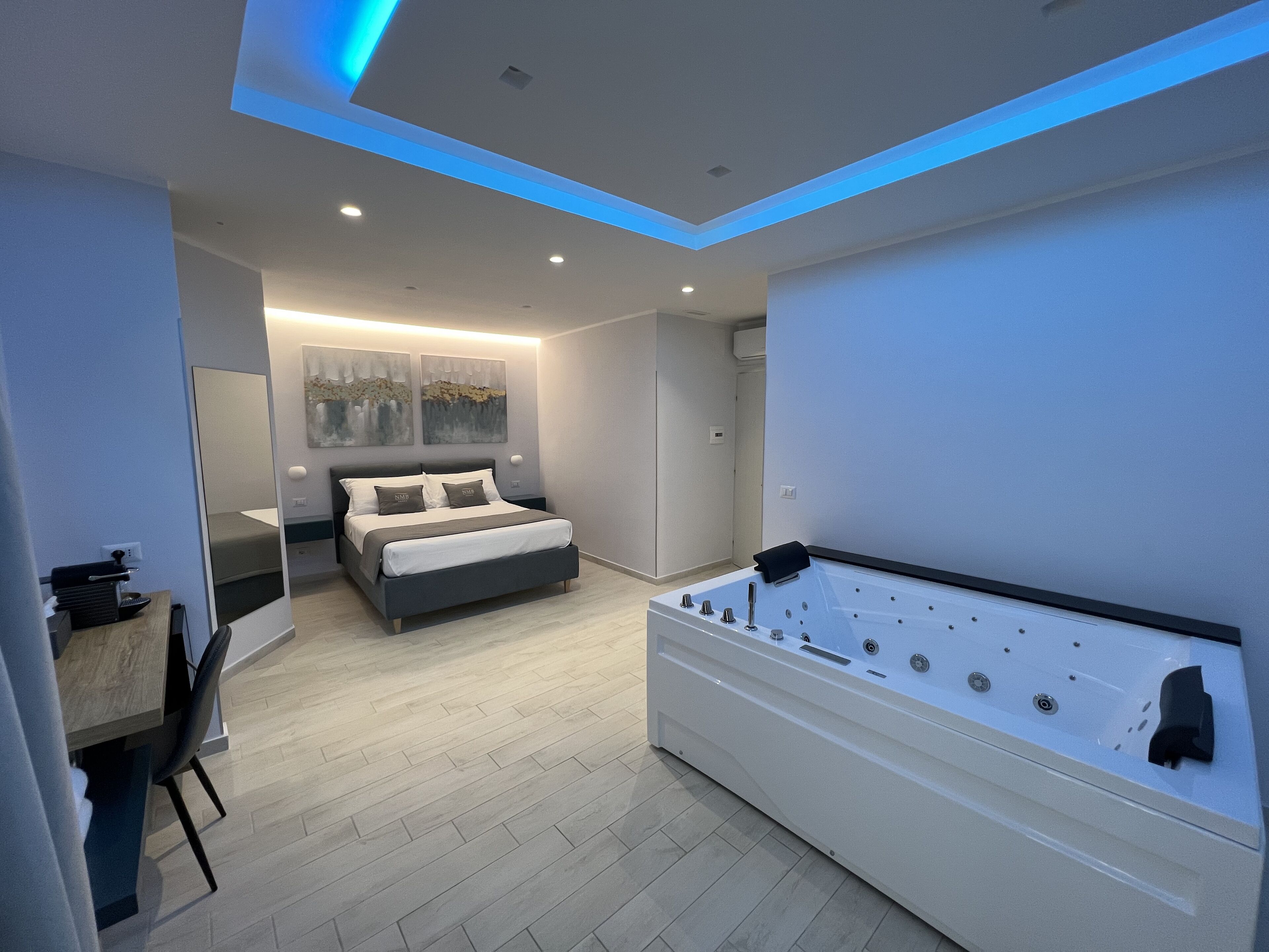 Un dormitorio moderno con una cama grande, una zona de estar separada y una bañera estilo spa.