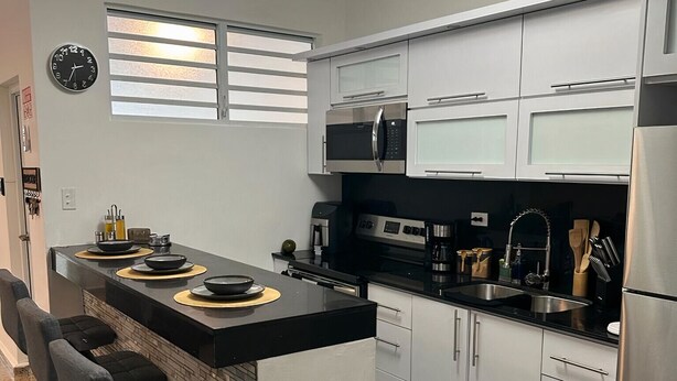 Una cucina moderna con isola centrale, elettrodomestici in acciaio inossidabile e piano di lavoro nero.