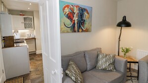 Una sala de estar con un sofá gris, almohadones estampados, una lámpara de pie negra y un cuadro abstracto colorido en la pared.