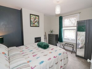 Un dormitorio con cama, cómoda, espejo, ventana con cortinas y un cuadro en la pared.