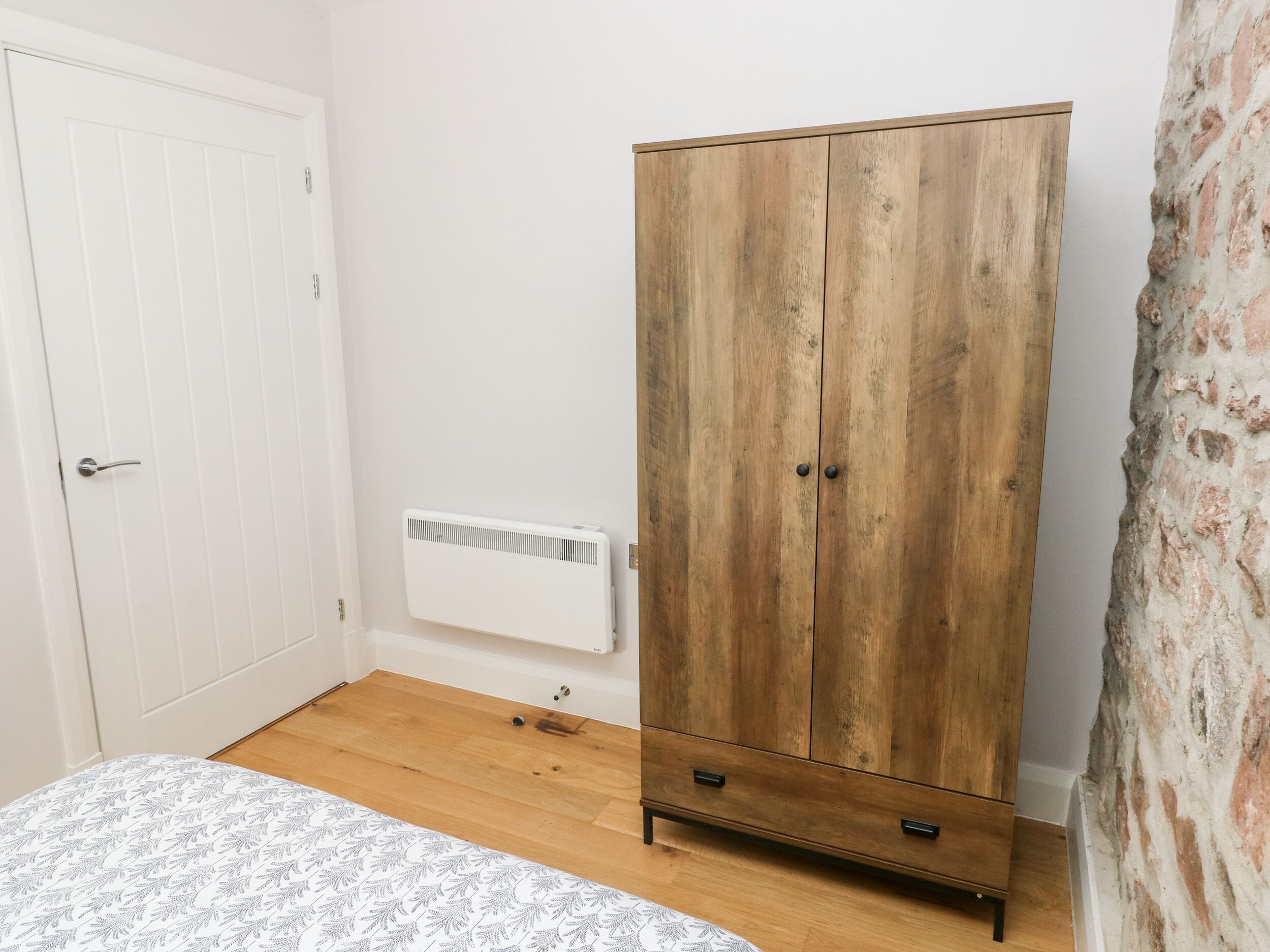 Una camera da letto con un armadio in legno, un termosifone e una coperta a fantasia.