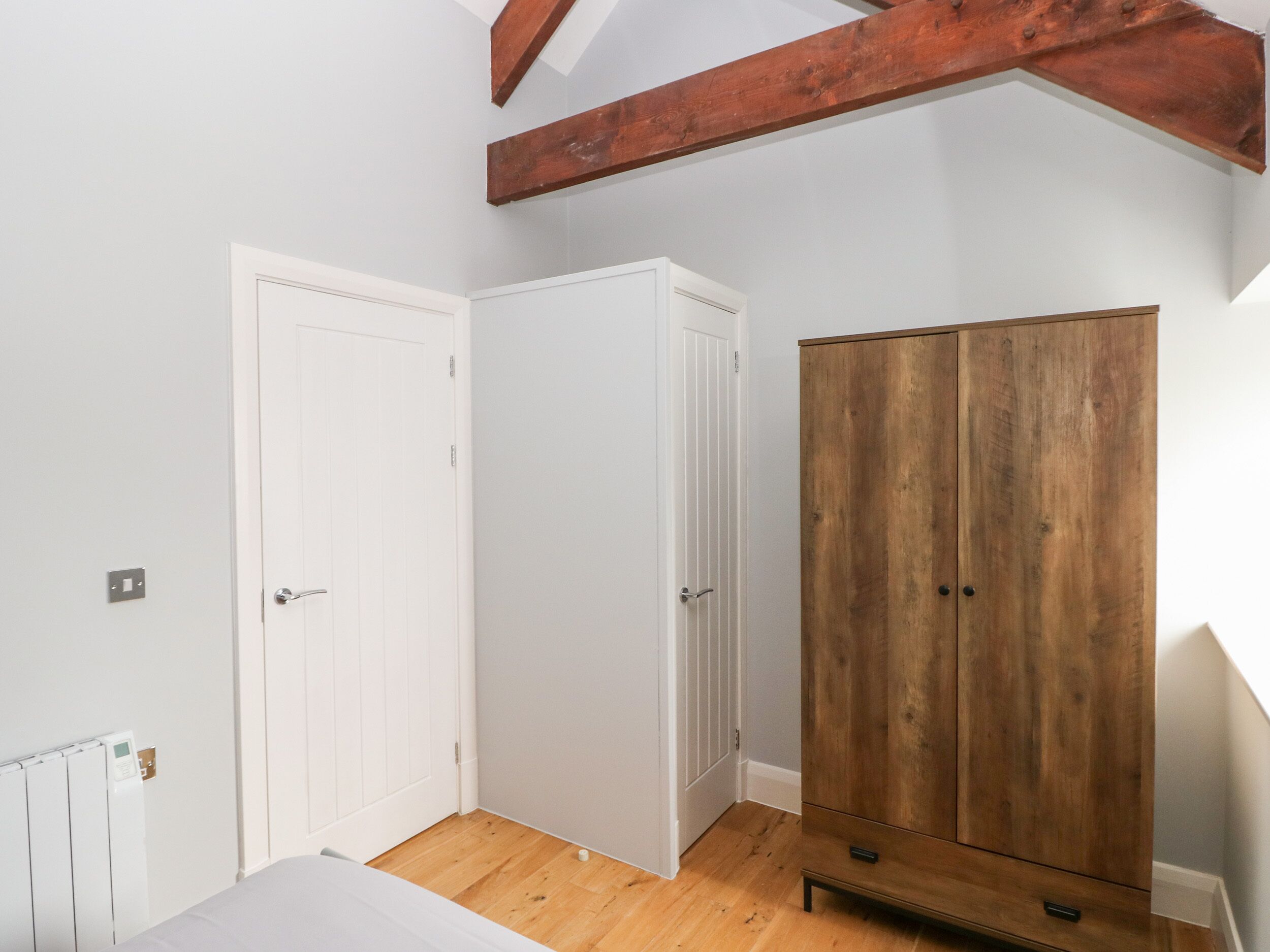 Ein Zimmer mit einer weißen Tür, einem weißen Kleiderschrank und einem Holzschrank.