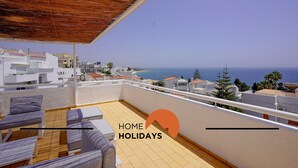 Una terraza en la azotea con vista al mar, amueblada con un sofá y una mesa.