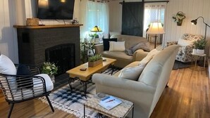 Una sala de estar acogedora con chimenea, un sofá, una mesa de centro y un televisor colocado sobre la chimenea.