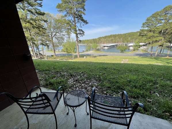 Enjoy a serene lakeside retreat with a patio offering a bridge view, comfortable seating, and a tranquil lawn setting.