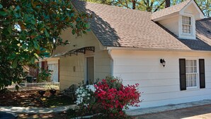 A single-story house with a gabled roof, a covered porch, and a small front yard with a white picket fence and flowering plants. - Magnolia Suite Vacation Home -Private Entry, Old Canton N. Jackson (Jackson)