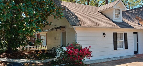 A single-story house with a gabled roof, a covered porch, and a small front yard with a white picket fence and flowering plants. - Magnolia Suite Vacation Home -Private Entry, Old Canton N. Jackson (Jackson)