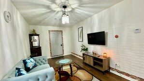 A living room with a sofa, a coffee table, a TV, and a fireplace. - Magnolia Suite Vacation Home -Private Entry, Old Canton N. Jackson (Jackson)